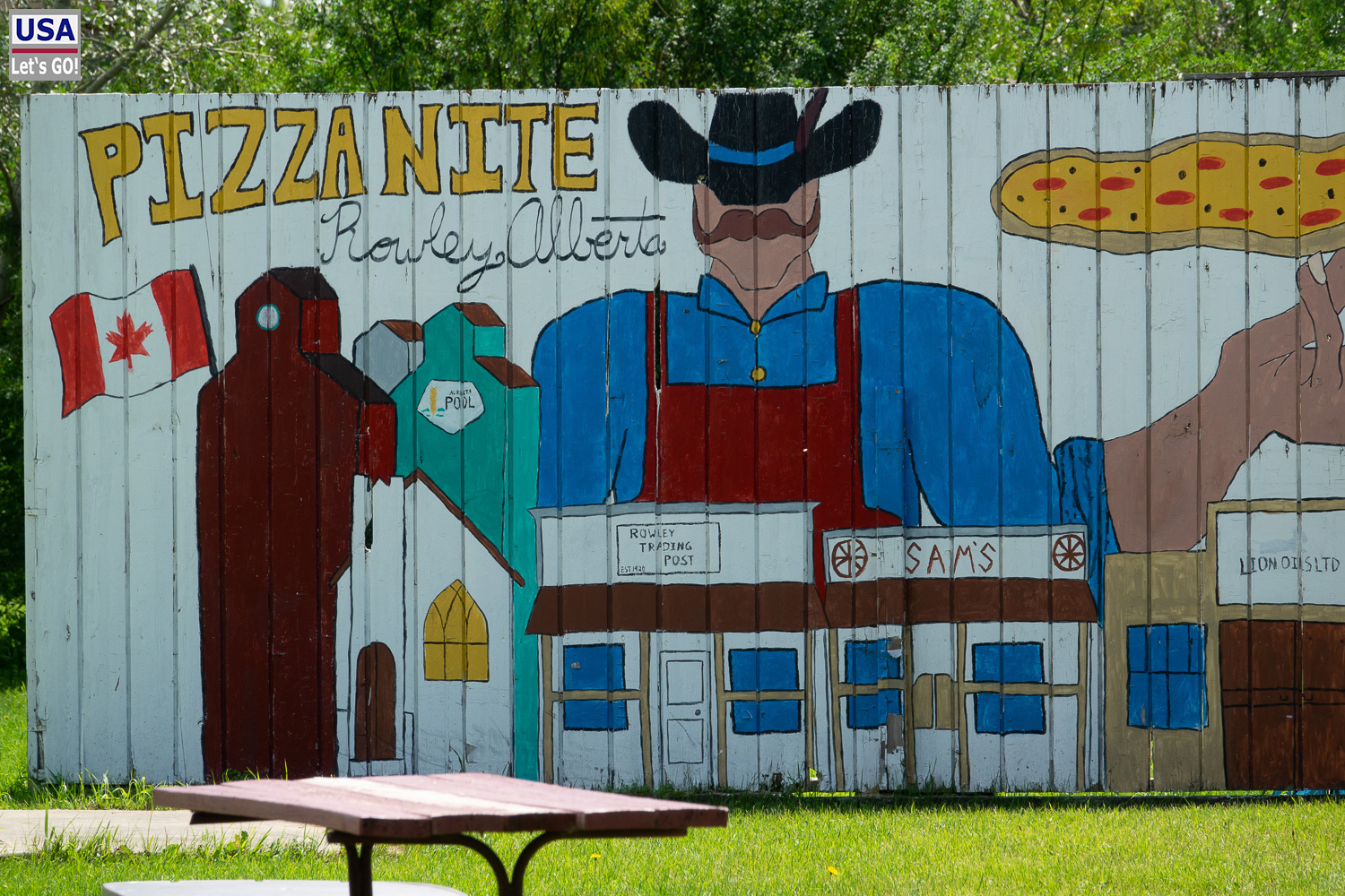 Wandbild „Pizza Nite Rowley, Alberta“ mit Cowboy, Getreidesilos und Main Street