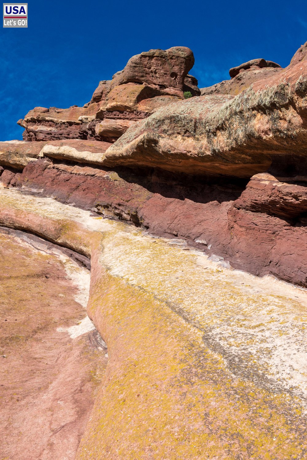 Nahaufnahme der geschichteten Sandsteinformationen mit gelben Flechten am Red Rocks Amphitheatre